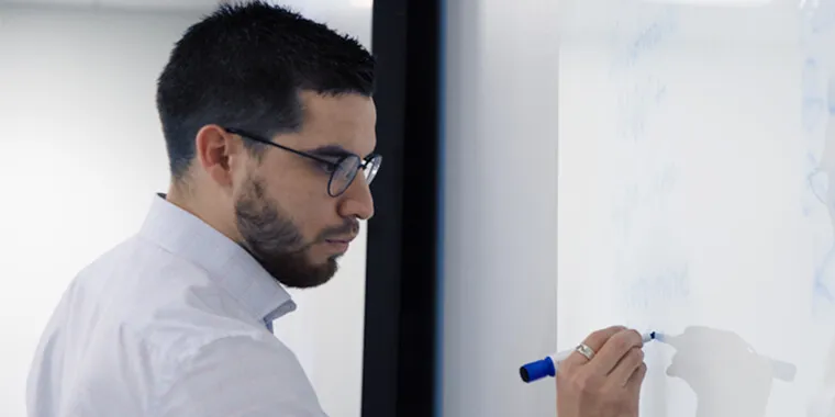 Man writing on white board with blue pen
